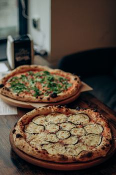 Two delicious freshly baked pizzas presented on a wooden table setting.