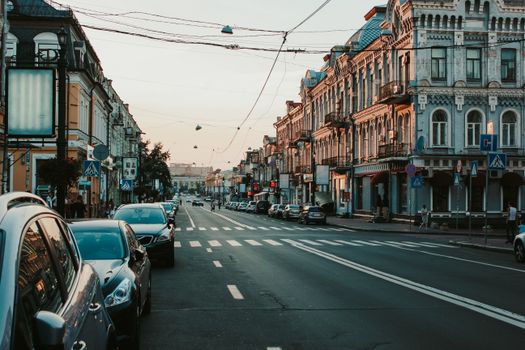 Historic Kyiv street scene with classic architecture and people crossing during sunset.