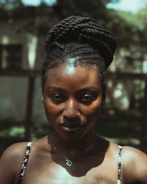 Free Close-up of a woman with braided hair under sunlight, outdoors setting. Stock Photo