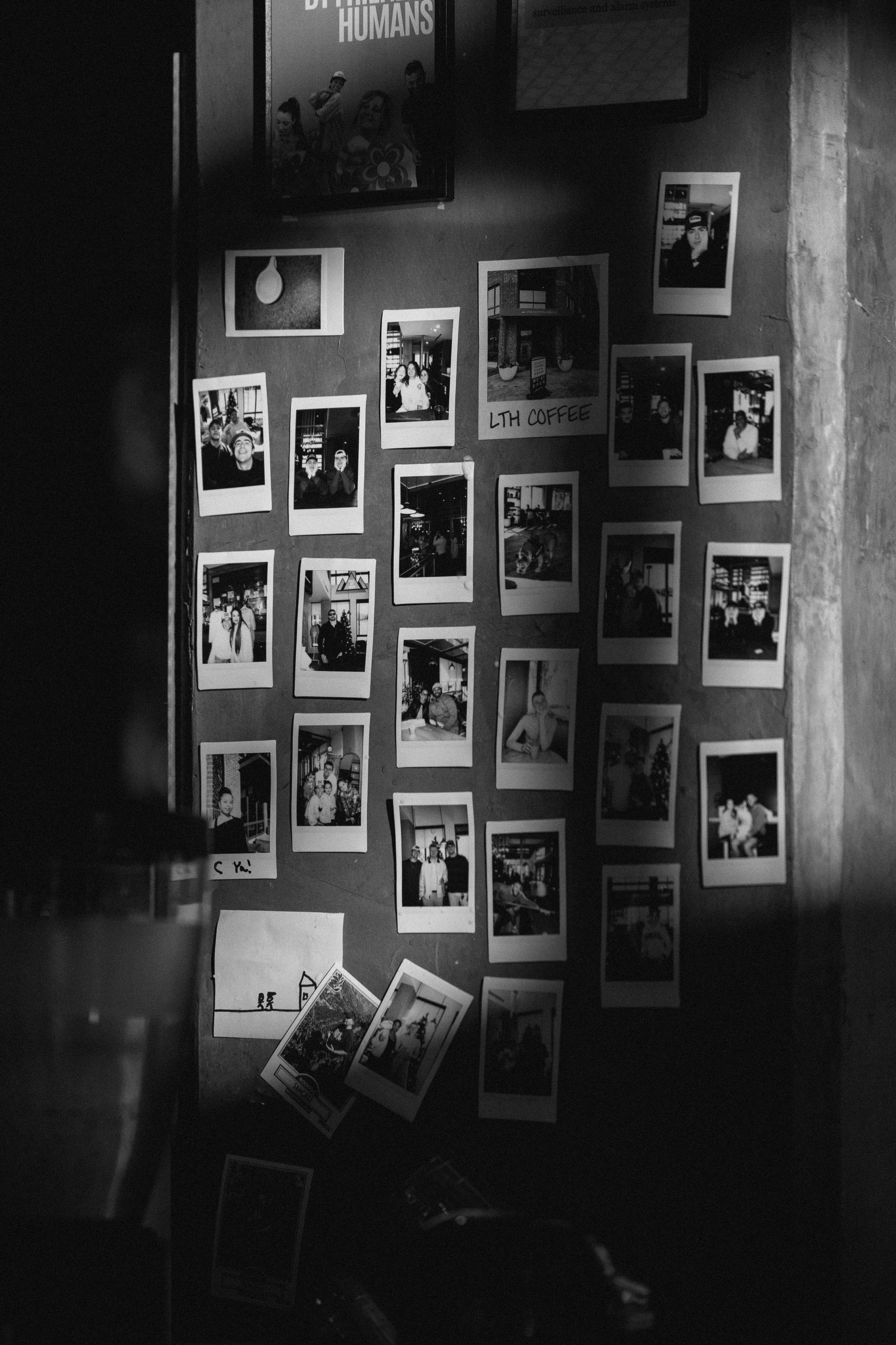grátis Uma coleção de Polaroids em preto e branco exibida na parede de um café em Charlotte, Carolina do Norte. Foto profissional