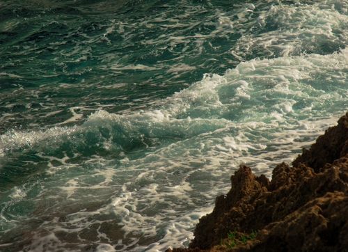 Free Dynamic waves crashing against a rocky shoreline, capturing the ocean's relentless energy. Stock Photo