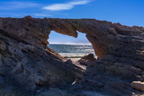 Free Stunning natural rock arch by the sparkling sea in Torrevieja, Spain, under a clear blue sky. Stock Photo