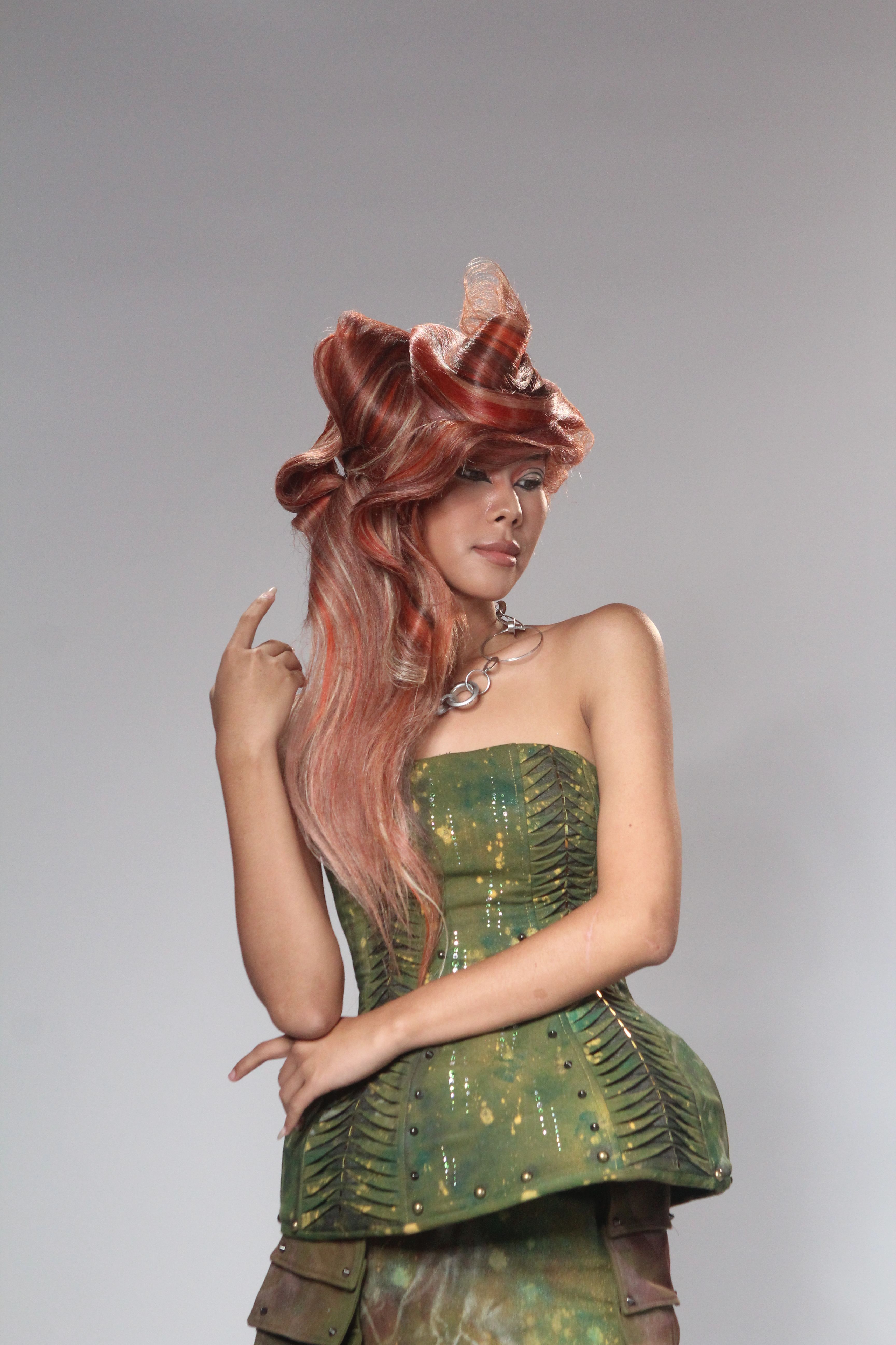 Young woman in a unique hairstyle and fashionable outfit posing elegantly in studio light.