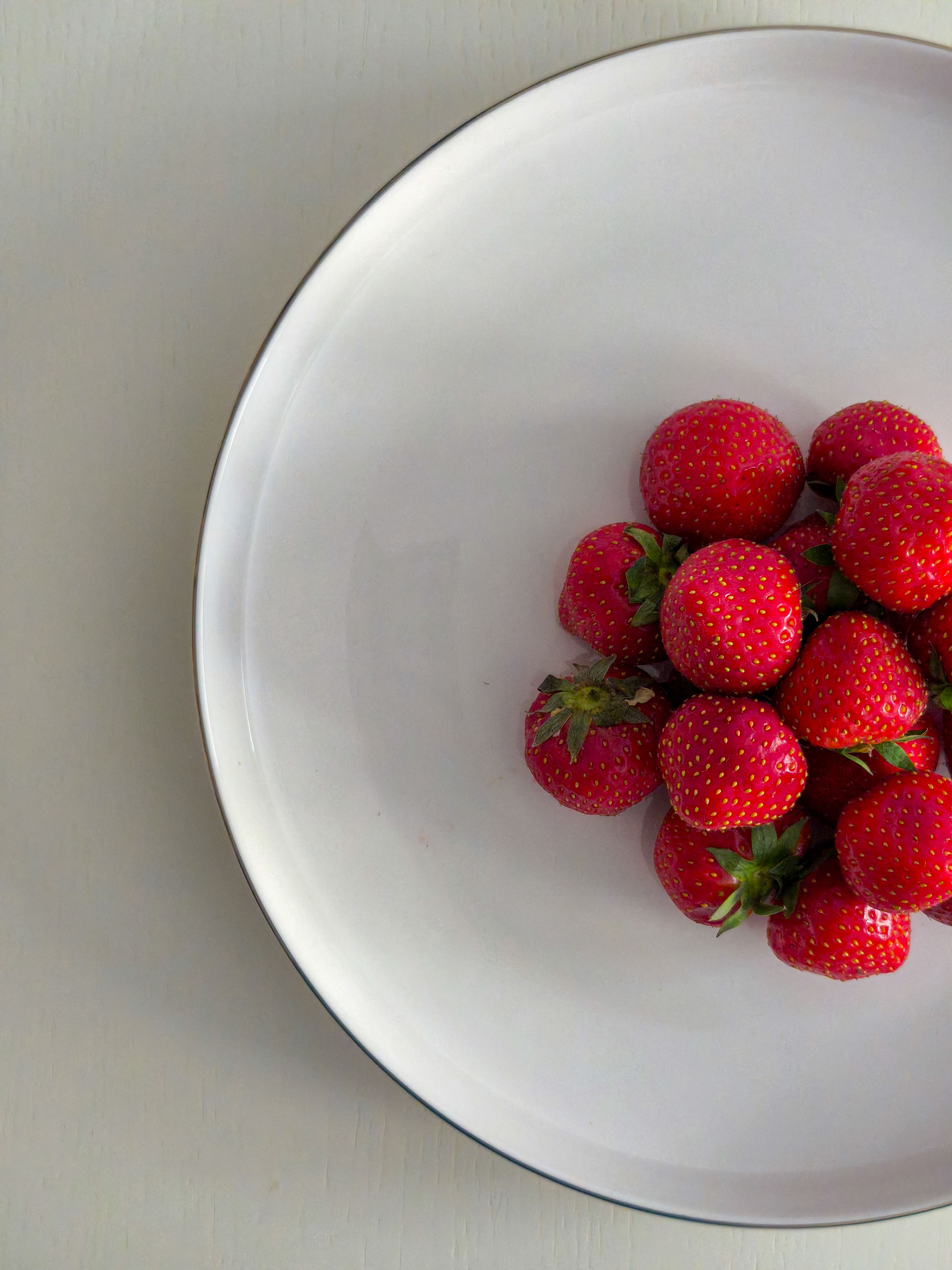A close-up shot of vibrant red strawberries in a simple white bowl, highlighting freshness and texture.