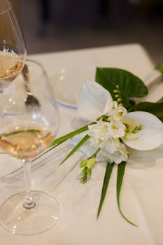 A classy table setup featuring white flowers and a wine glass, highlighting elegance.