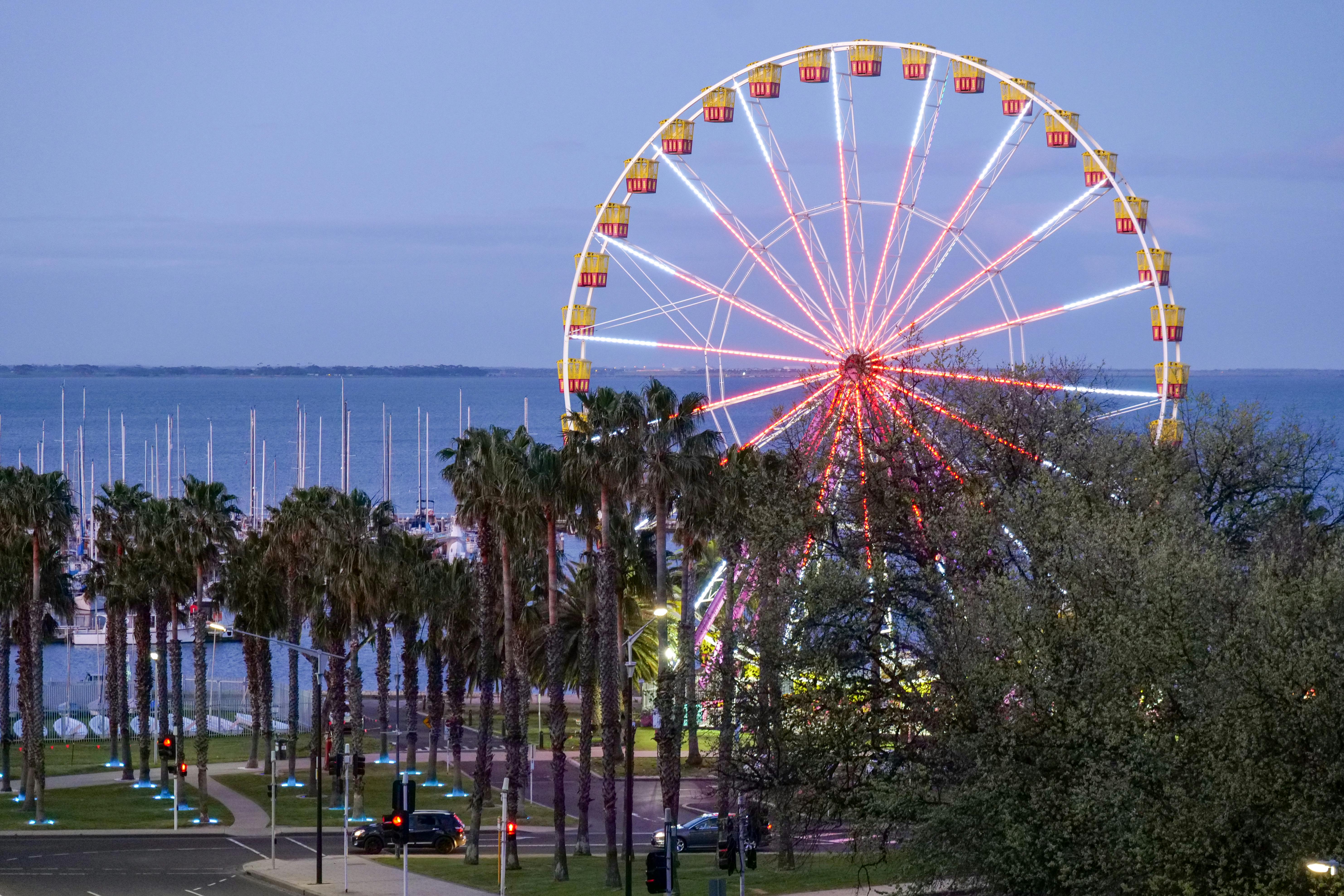 A vibrant Ferris wheel lights up the Geelong waterfront at dusk, offering a scenic adventure.