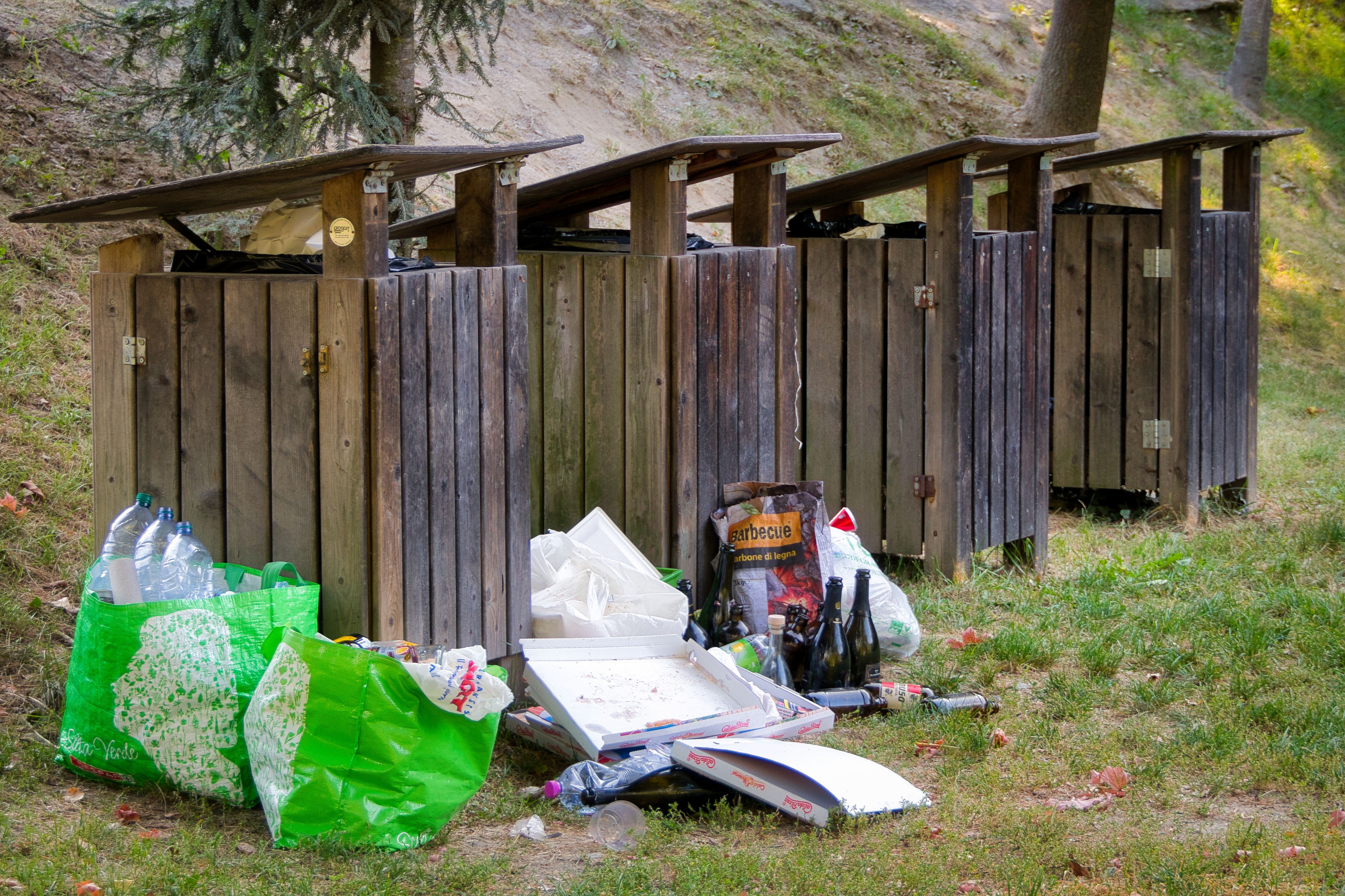 Overflowing garbage bins in a park in Meran highlight littering issues.