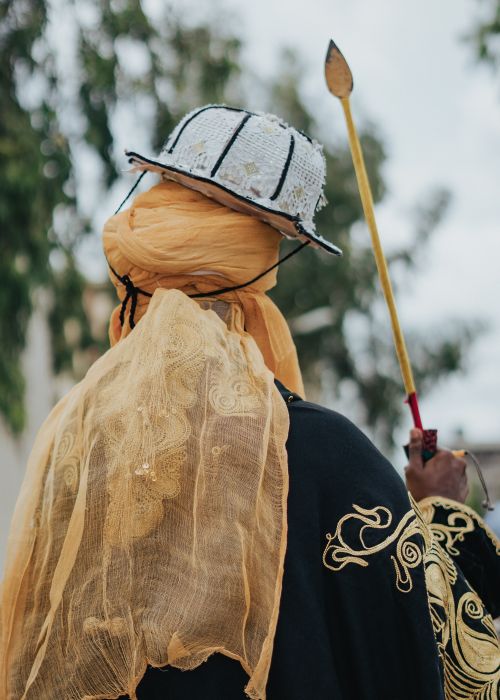 Free Person in traditional clothing holding a decorative stick in an outdoor setting. Stock Photo