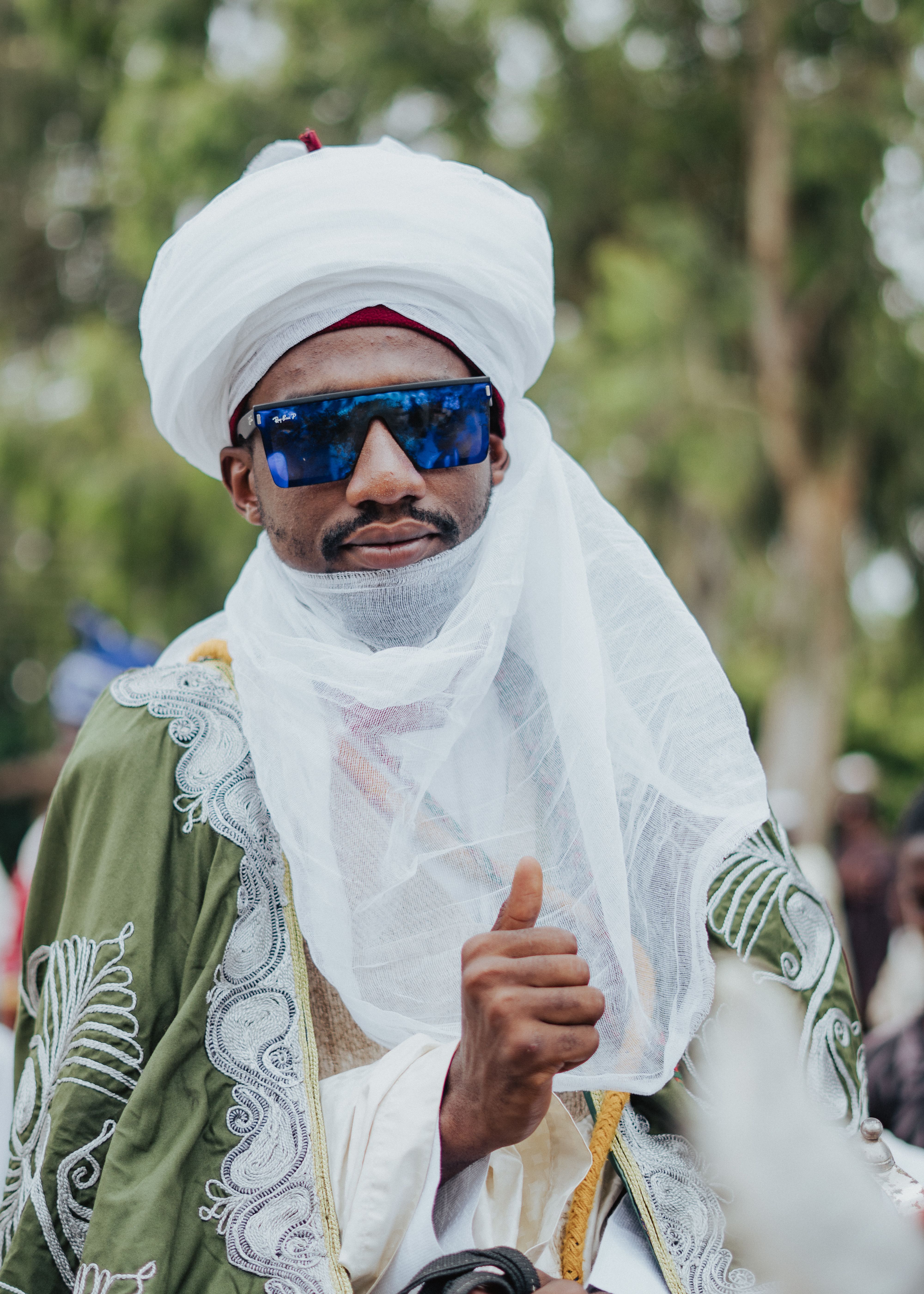 Man in traditional African attire and modern sunglasses, outdoors.