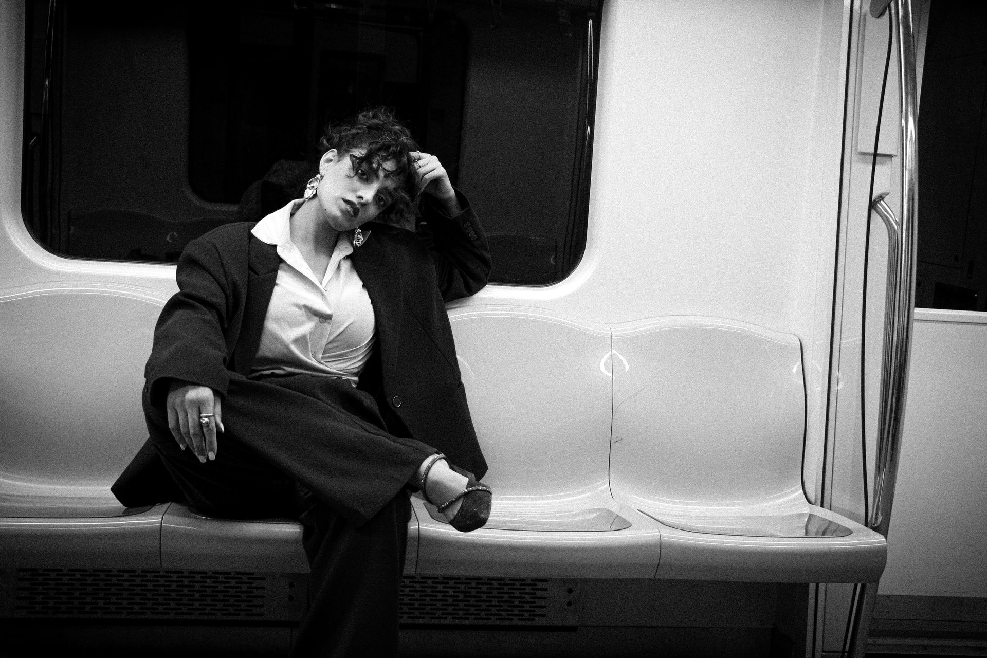 Woman in fashionable oversized suit posing in a subway car. Artful, modern vibe.