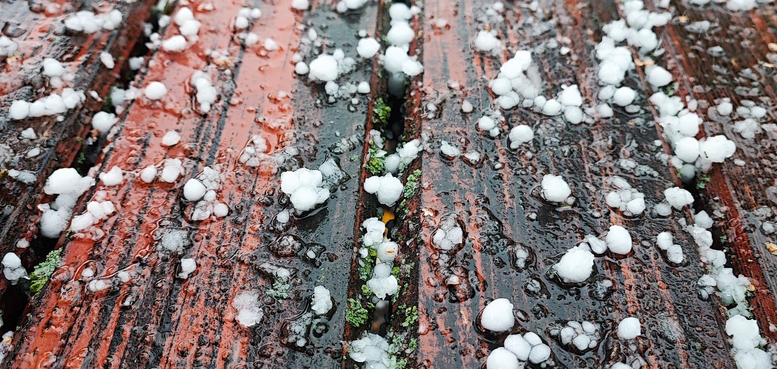 Hailstones scattered on a wet deck after a storm