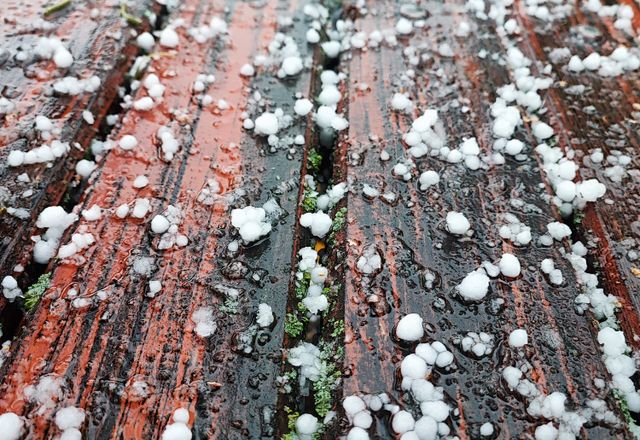 Hailstones scattered on a wet deck after a storm
