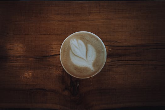 A close-up of a latte with intricate latte art on a rustic wooden table, perfect for coffee lovers.