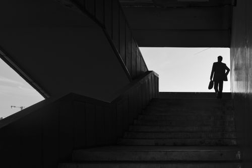 Free Silhouette of a businessman walking up a staircase in a modern urban setting. Stock Photo