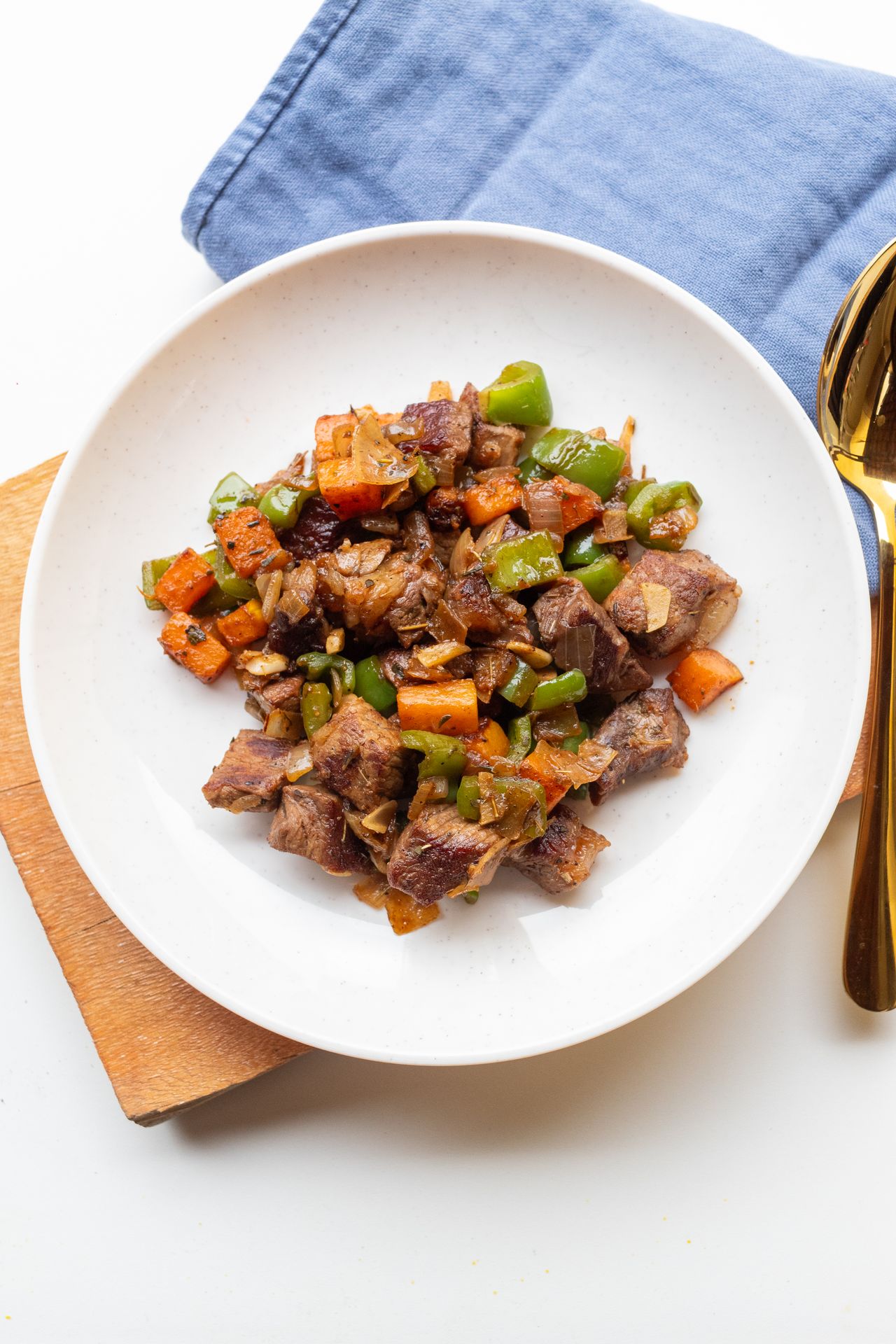 Seared beef strips with grilled vegetables on a white plate