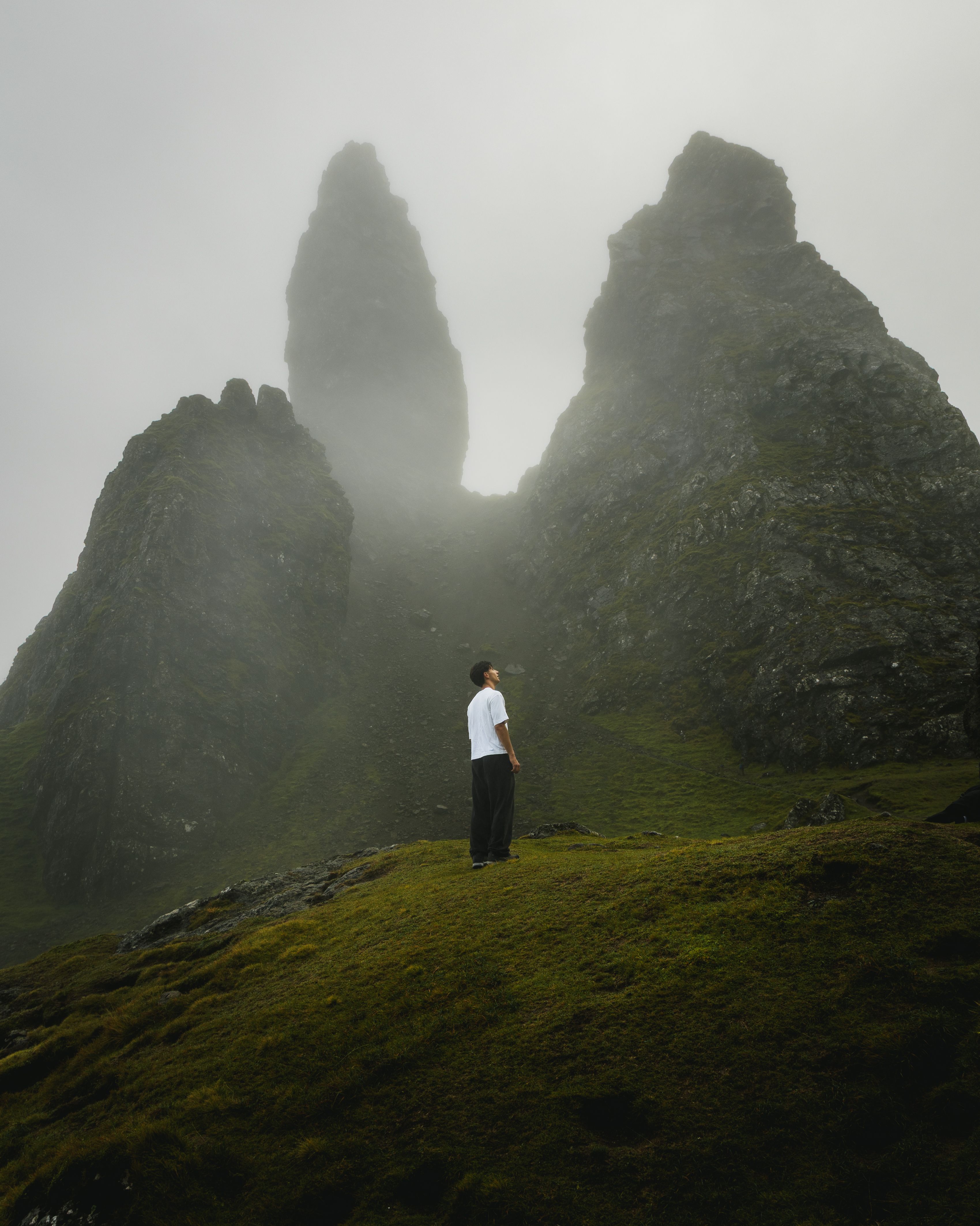 A person admires the iconic Old Man of Storr rock formation enveloped in mist on the Isle of Skye.