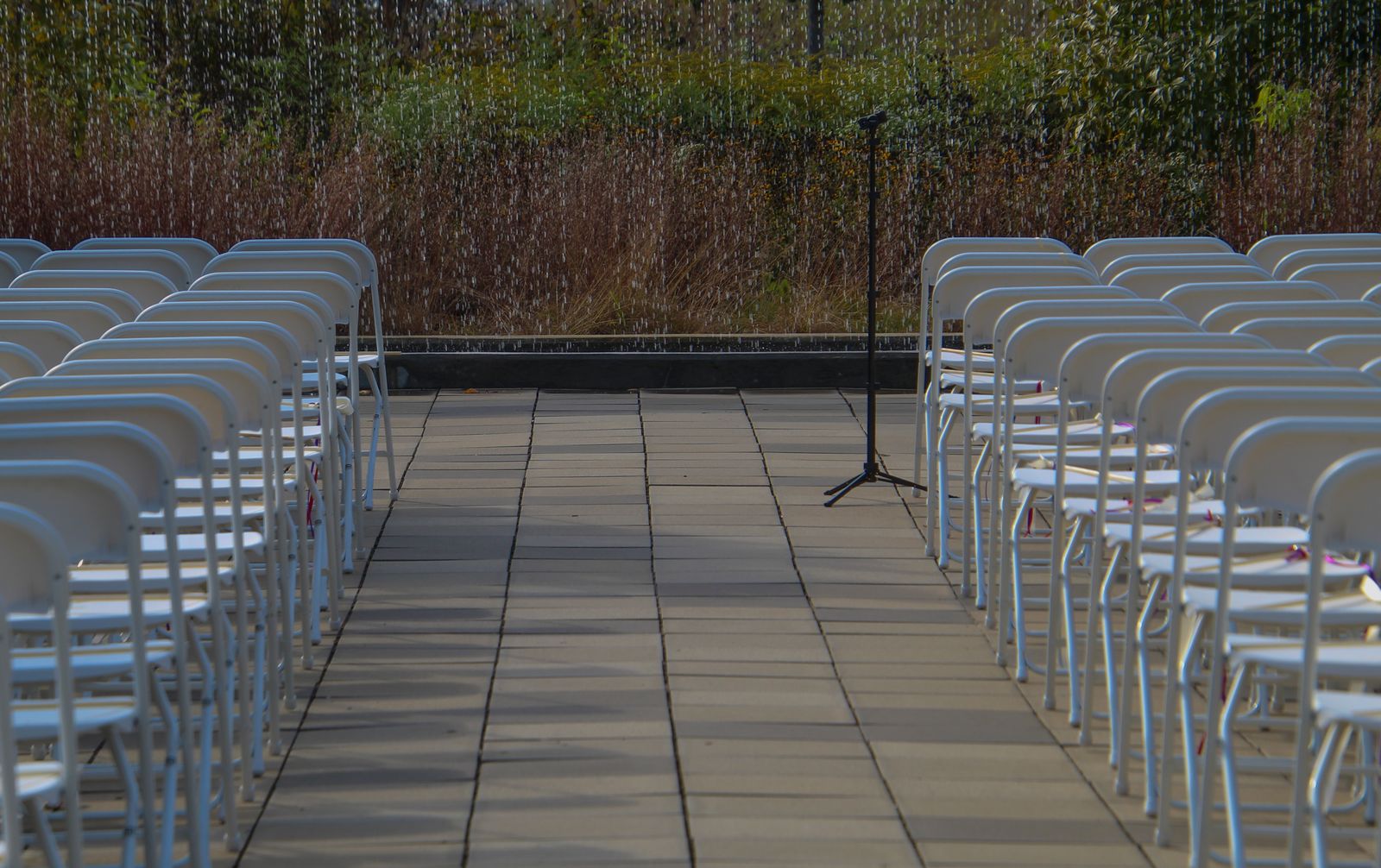 Outdoor wedding ceremony setup with white chairs and a microphone stand