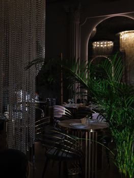An elegant restaurant interior featuring crystal chandeliers and lush greenery.