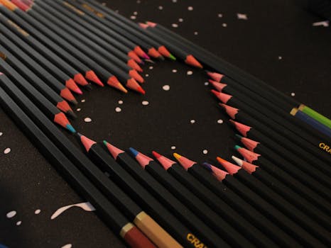 A creative heart shape formed with colorful pencils on a dark surface, ideal for art-themed projects.