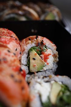 Detailed view of a sushi roll featuring avocado, fish roe, and sesame seeds, captured indoors.