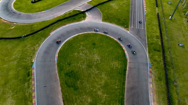 Aerial photograph of go-karts racing on a winding outdoor track, capturing the thrill of motorsports.