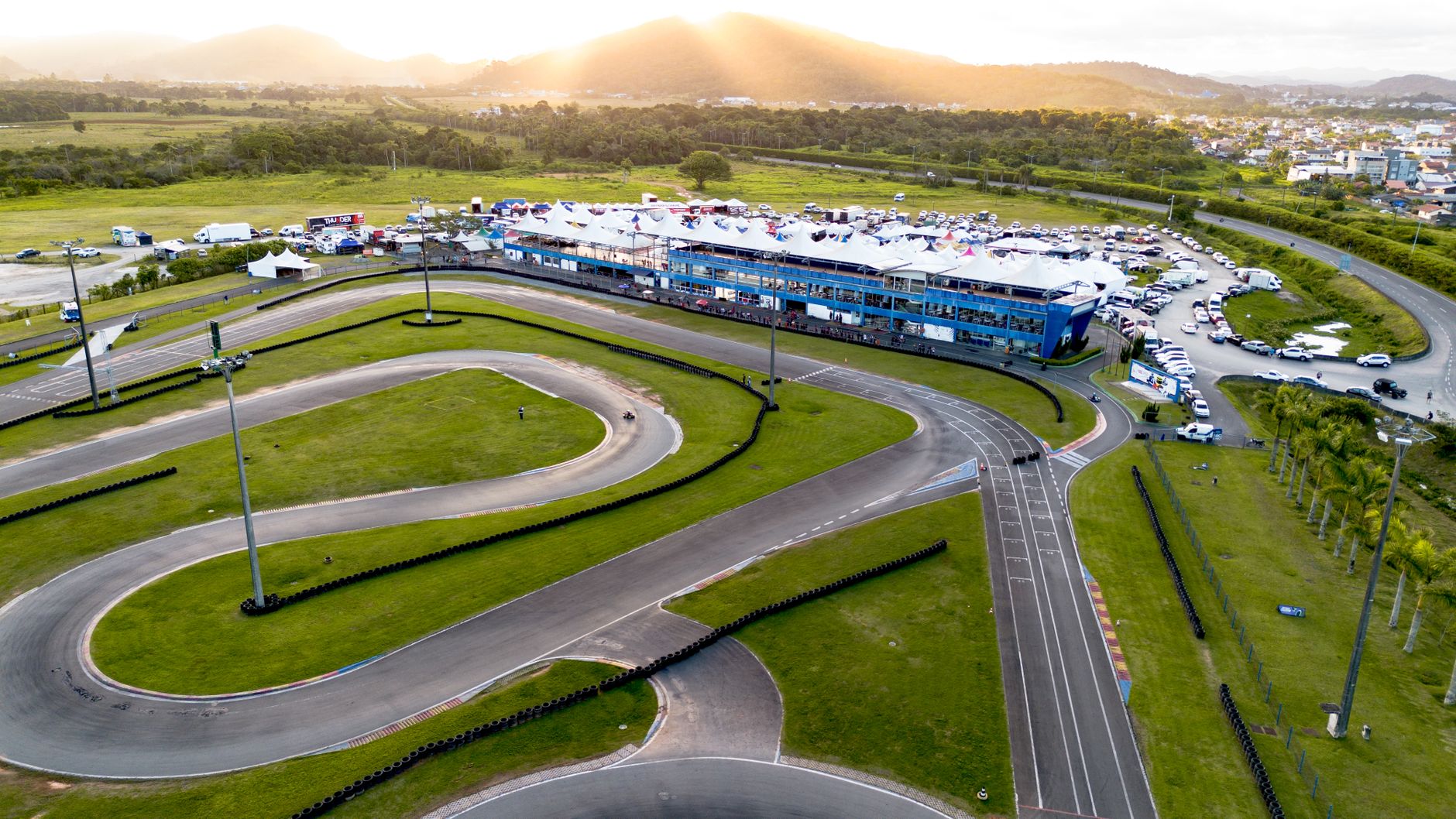 Aerial photograph of a go-kart track surrounded by green landscape during sunset.