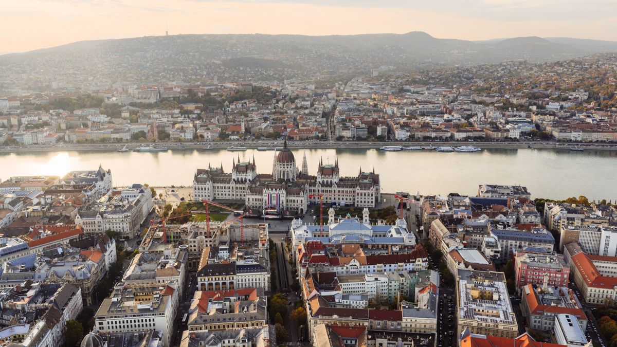 Stunning aerial view of Budapest featuring the iconic Hungarian Parliament Building along the Danube River at sunset.