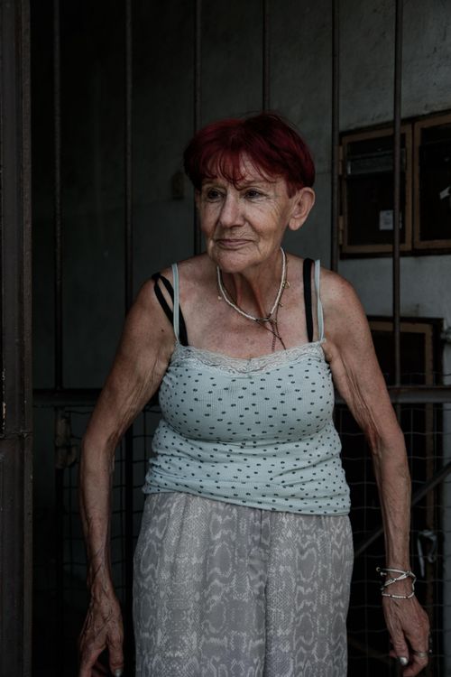 Free Portrait of an elderly woman with red hair standing indoors, displaying wisdom and life experiences. Stock Photo