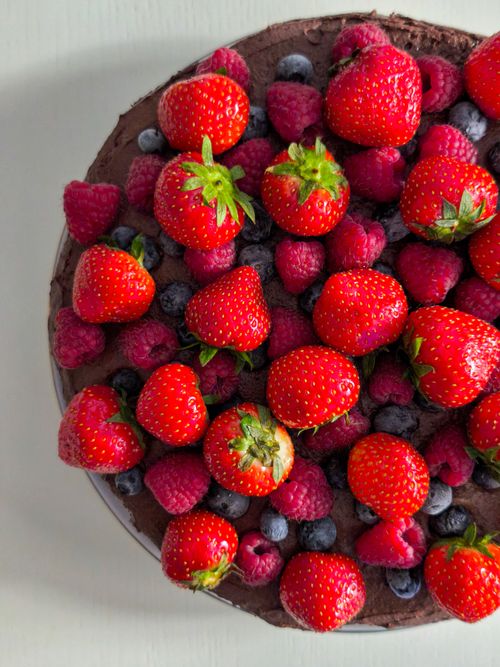 Free Indulge in this vibrant chocolate cake topped with fresh strawberries, raspberries, and blueberries. Stock Photo