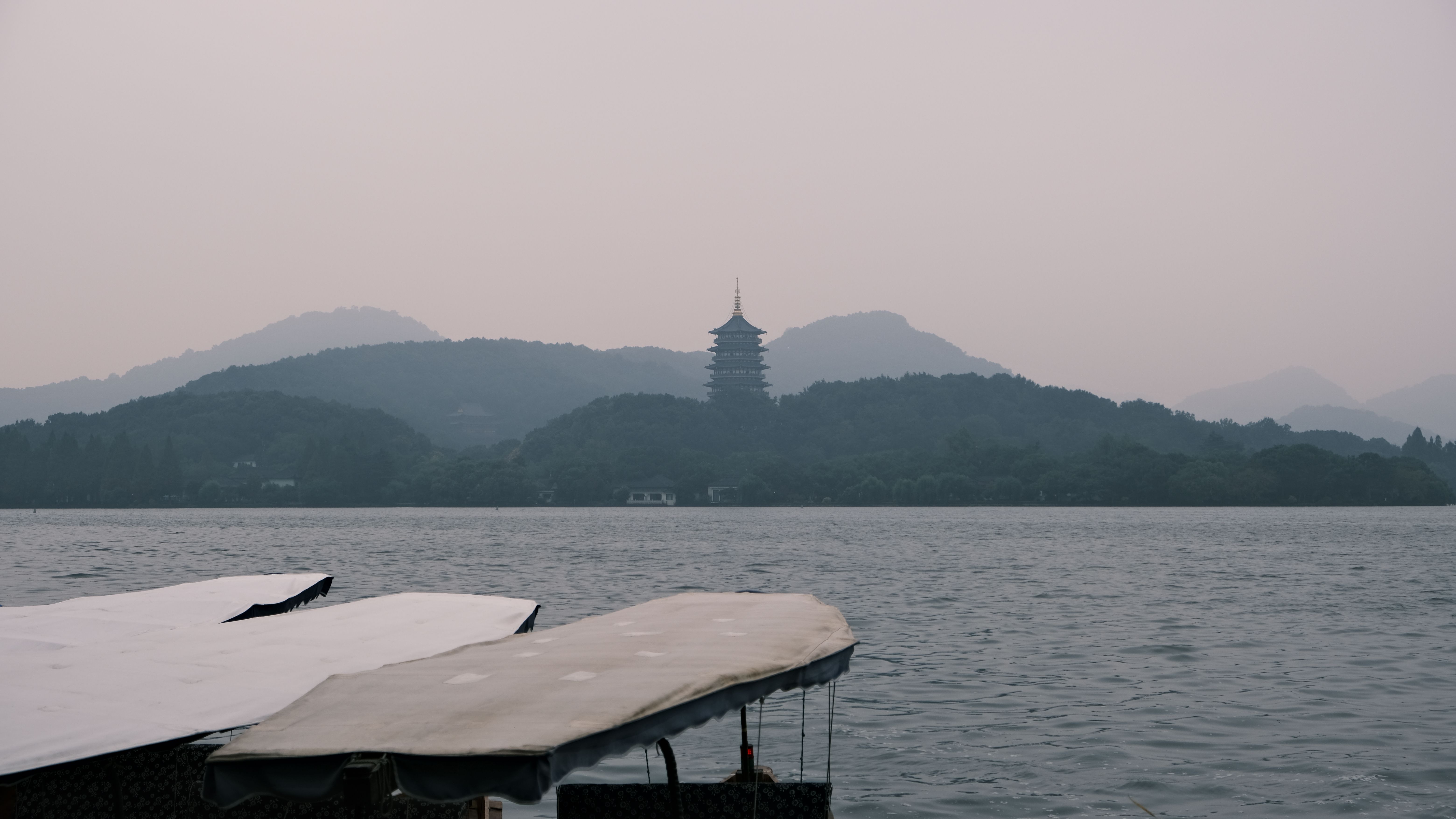 Calm West Lake waters with Leifeng Pagoda and misty mountains in Hangzhou, Zhejiang, China