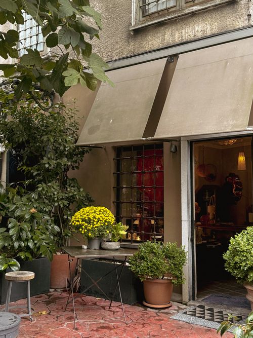 Free Cozy outdoor cafe with patio seating and lush plants, creating an inviting ambiance. Stock Photo