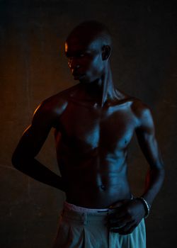 Dramatic portrait of a muscular man in low lighting, highlighting physique.