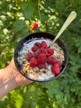 Fresh raspberries and granola served outdoors in Swedish summer garden.