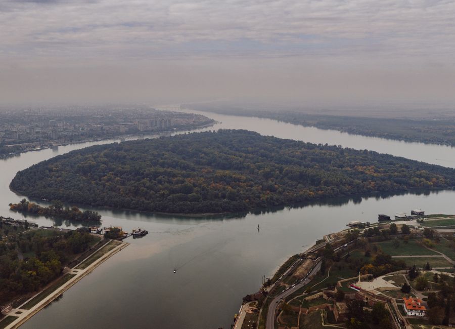 Stunning aerial shot of the river bend in Belgrade, Serbia, showcasing lush greenery and cityscape.