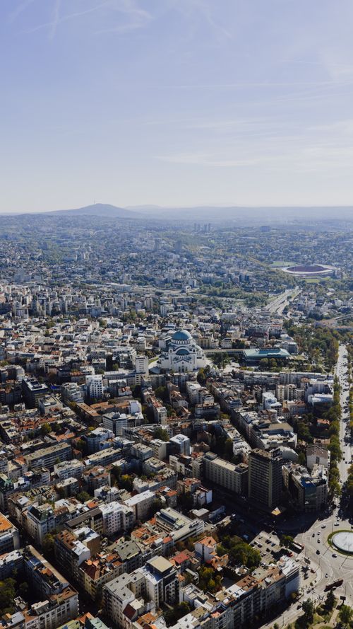 Free Drone shot capturing the urban landscape of Belgrade, Serbia with St. Sava Temple prominently visible. Stock Photo
