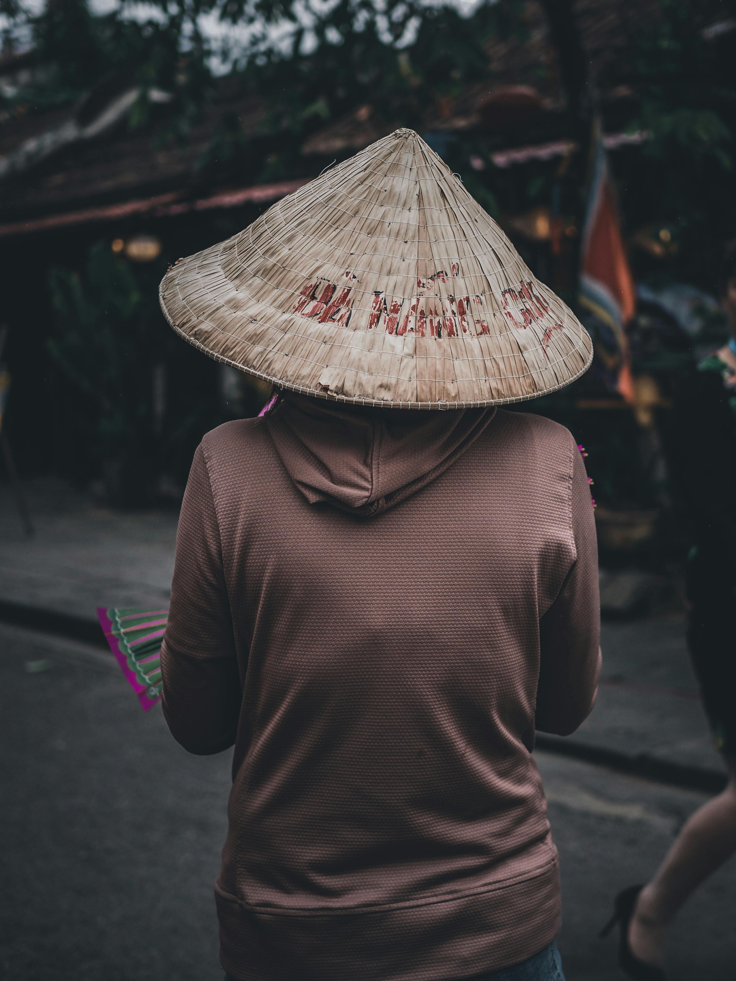 在室外环境中拍摄的，一个戴着圆锥形帽子的人走在安静街道上的后视图