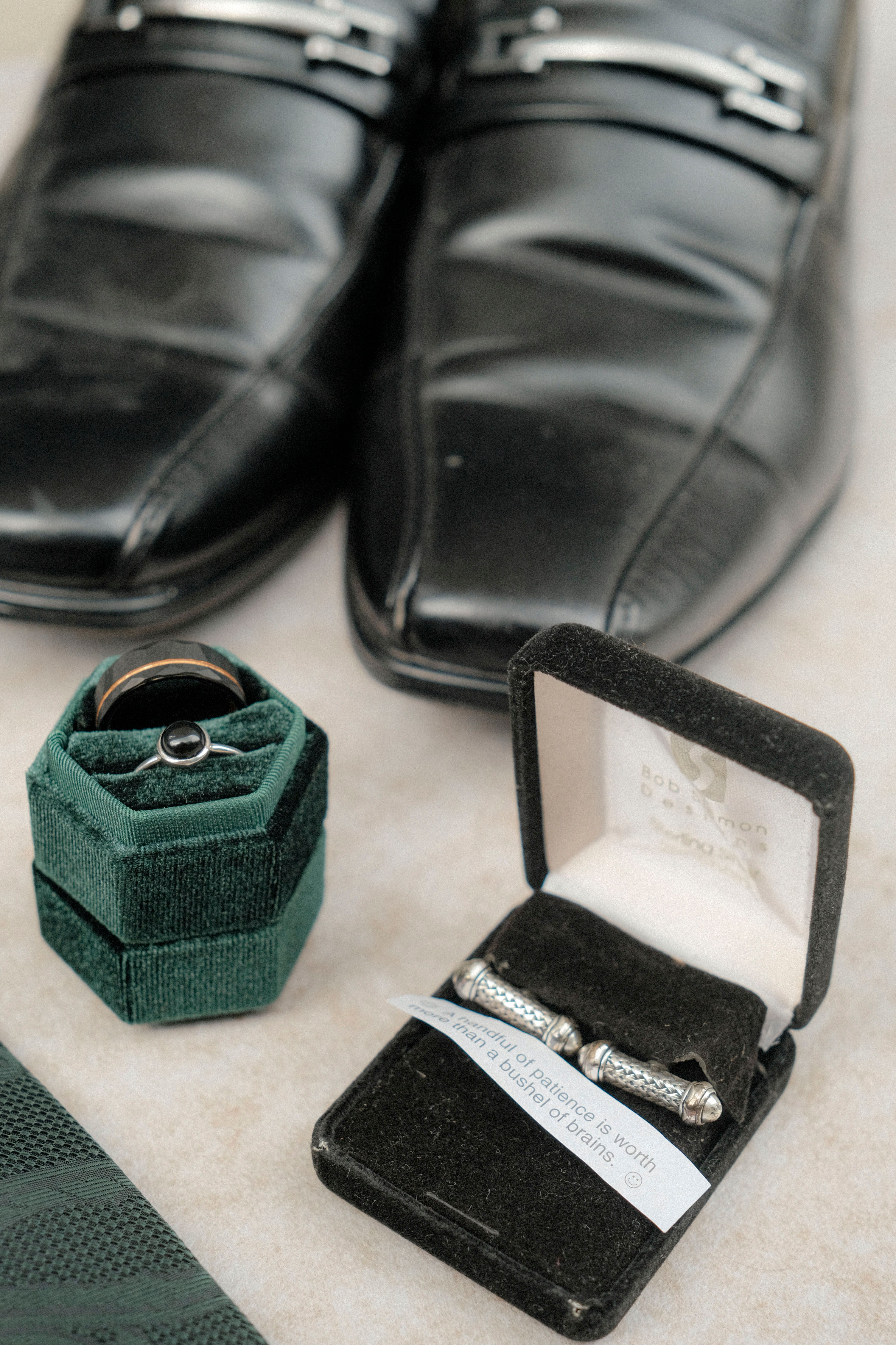 A collection of elegant men's accessories including black shoes, rings, and cufflinks.