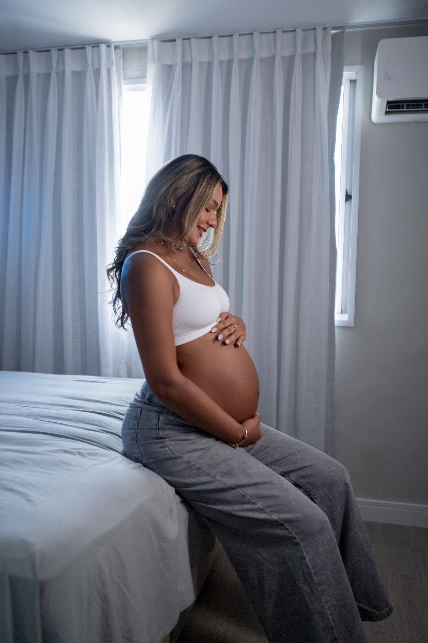 Femme enceinte assise confortablement sur son lit dans une chambre apaisante