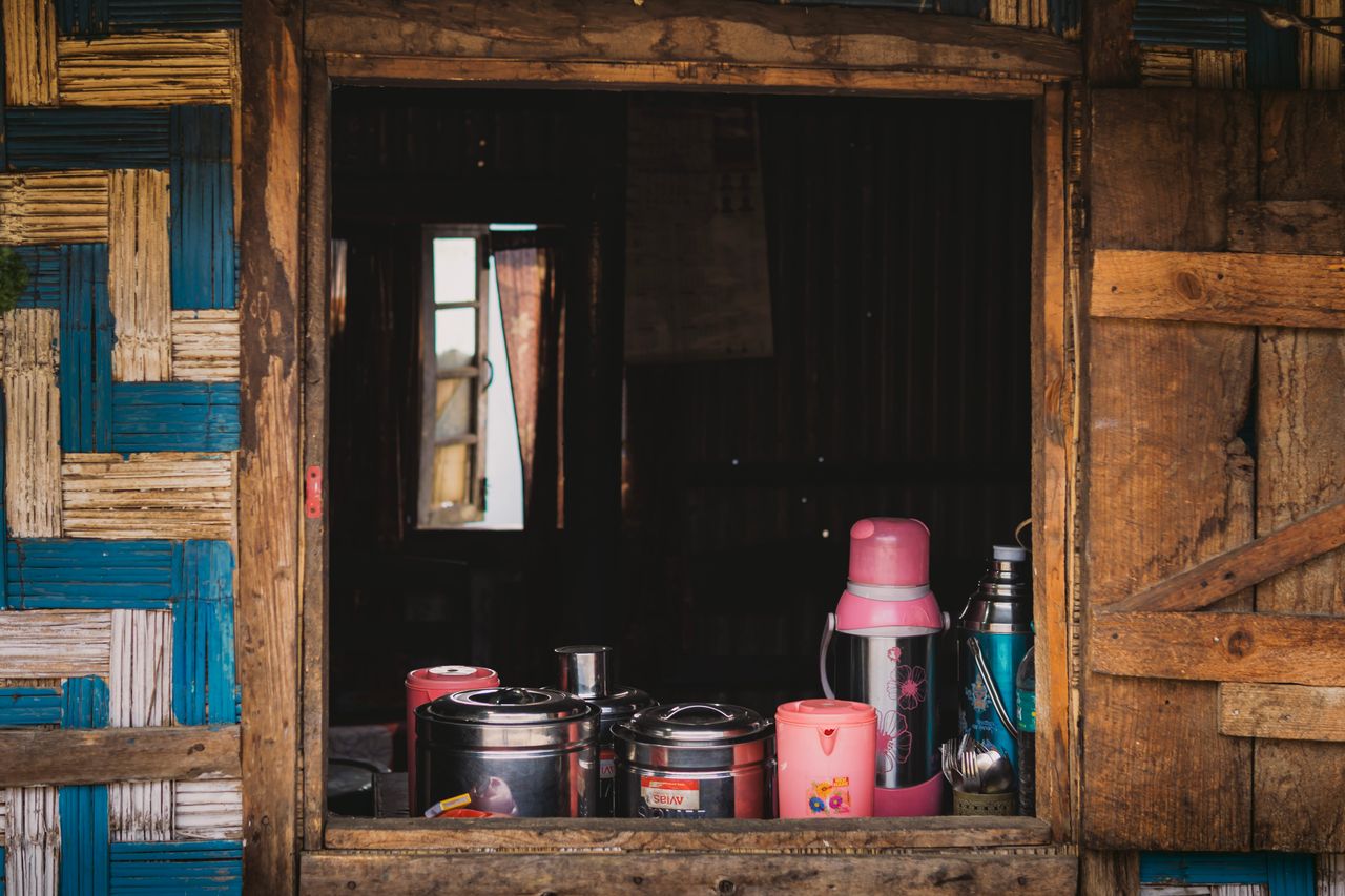 Rustic kitchen window with thermos and pots on wooden shelves