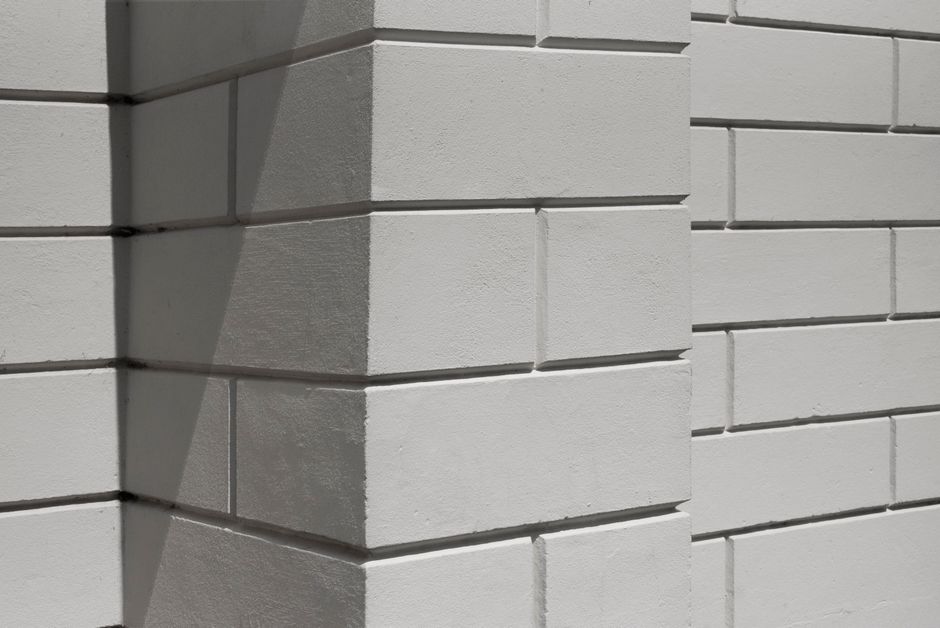 Close-up of a white brick wall with geometric shadows, ideal for backgrounds.