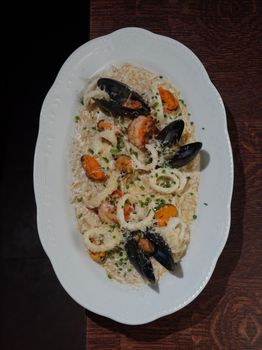 Delicious seafood risotto garnished with mussels and shrimp on a white plate.