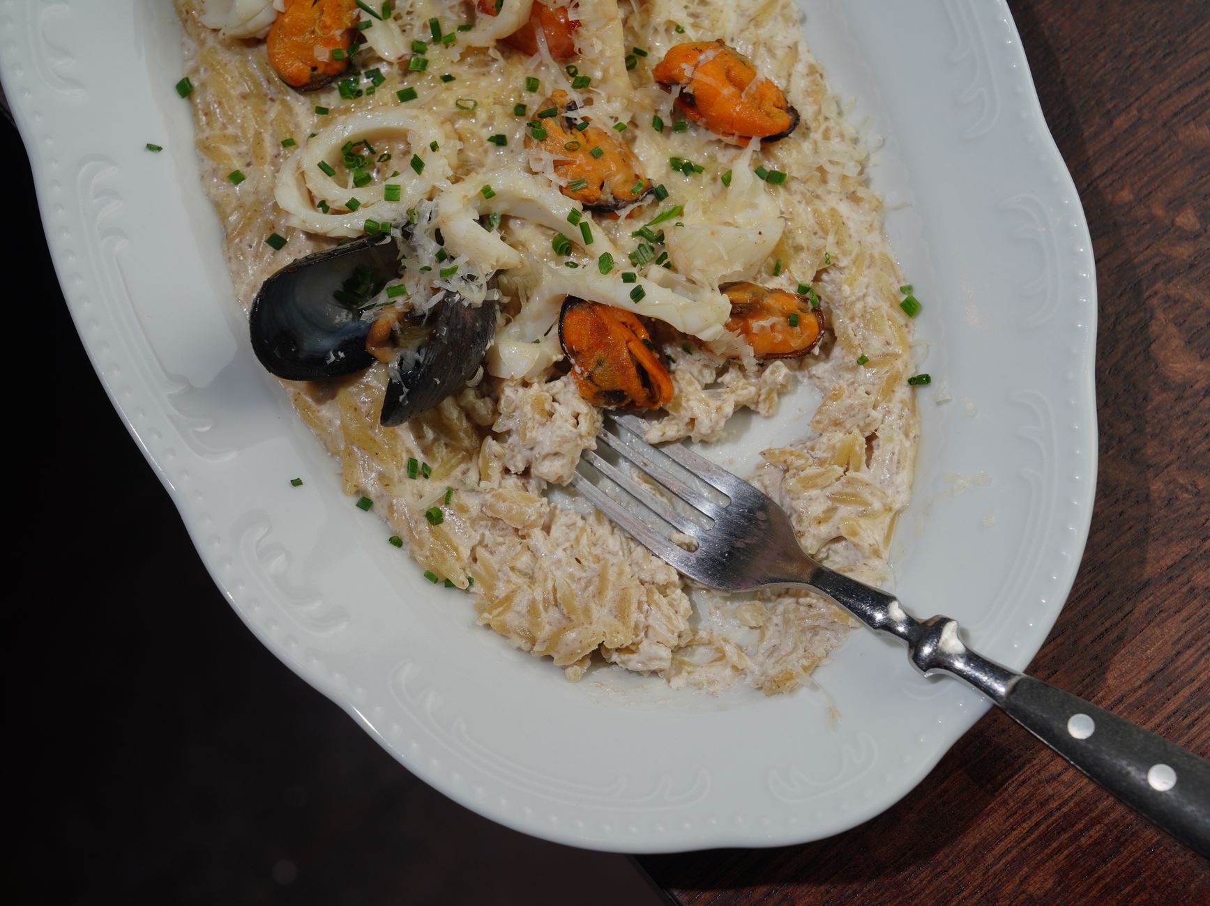 Serving bowl of cheesy orzo garnished with fresh herbs