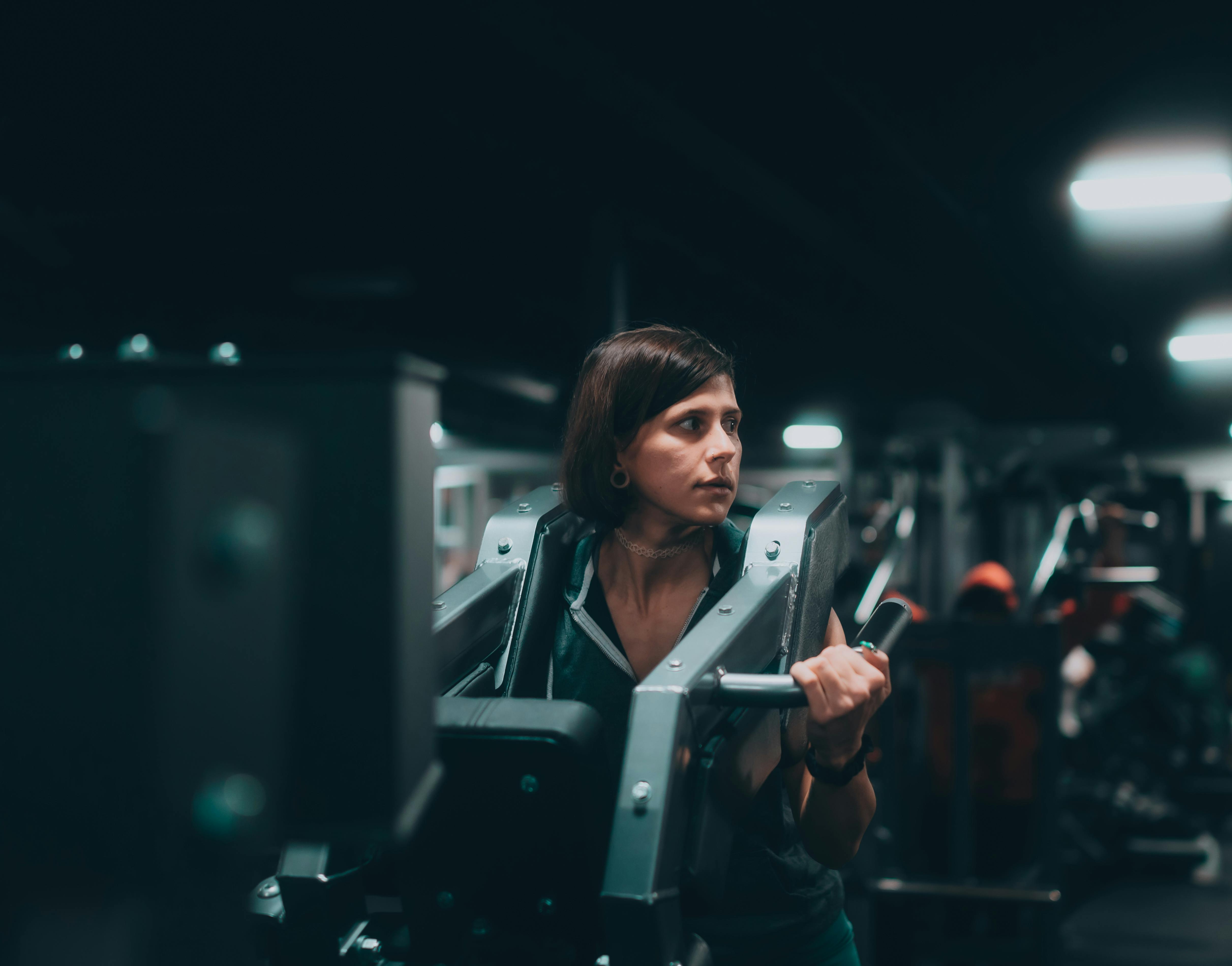 Gratis Una donna si allena intensamente su una macchina in una palestra moderna, dimostrando determinazione e forma fisica. Foto a disposizione