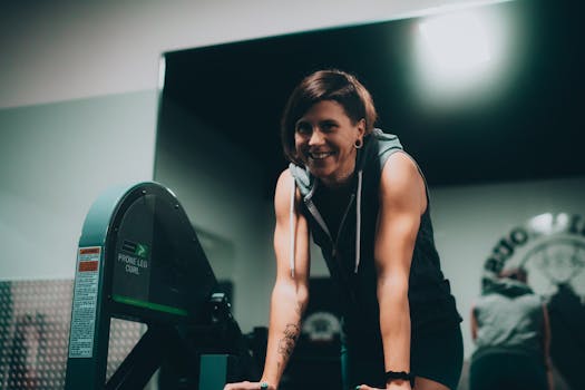 Active woman smiling during workout in gym setting with leg curl machine.