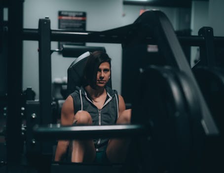 A woman intensely focused while using gym equipment, showcasing strength and determination.