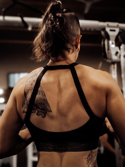Free Rear view of a strong athletic woman with a tattoo exercising in a gym, inspiring fitness and strength. Stock Photo