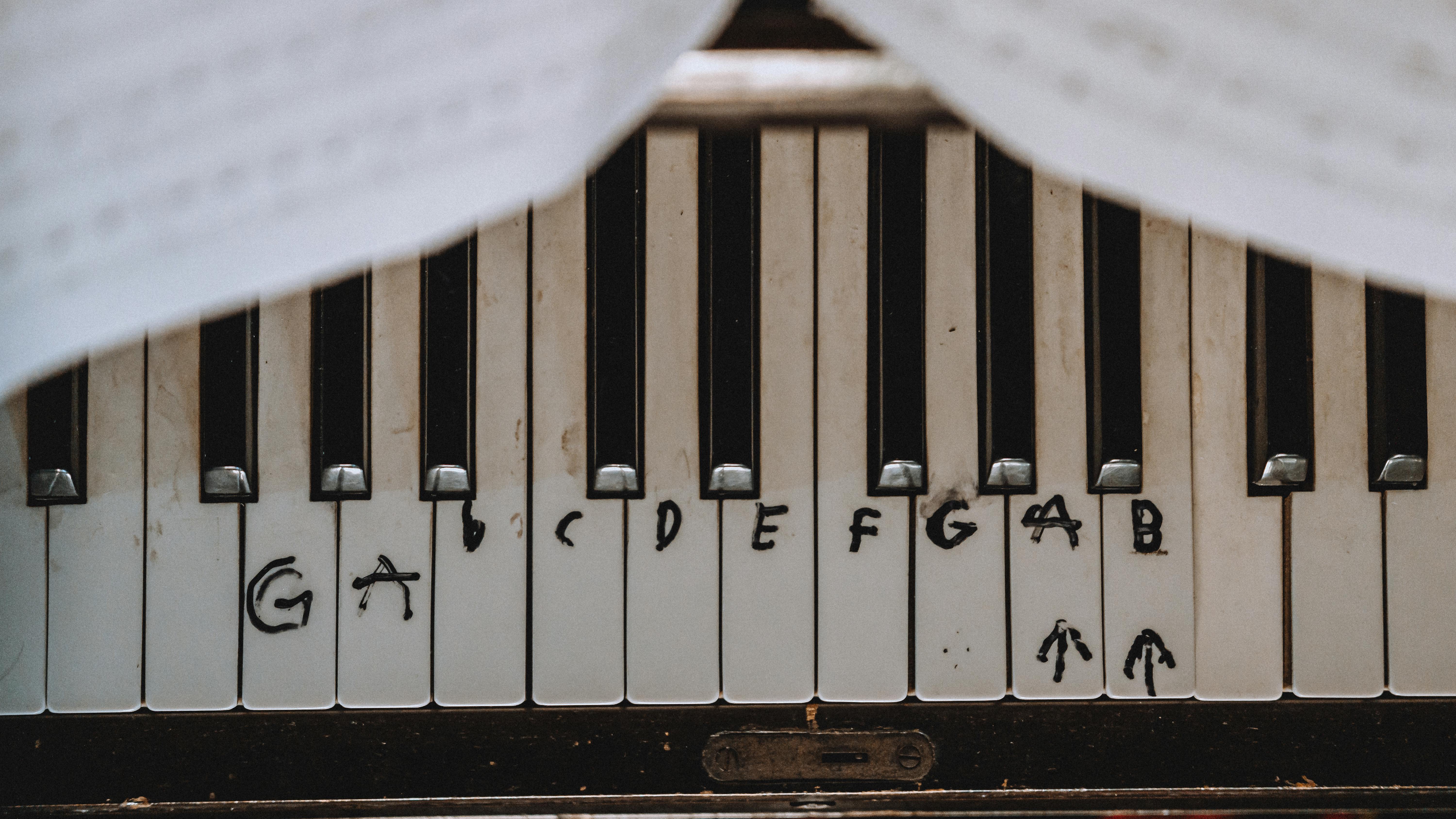 Detailed view of piano keys marked with handwritten musical notes for learning.