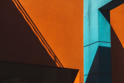 Free Vivid architectural forms with bold orange and blue colors creating striking geometric shadows. Stock Photo
