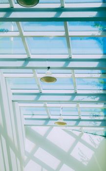 Bright modern ceiling with skylights and industrial lamps casting geometric shadows.