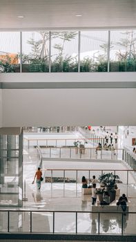 View of a spacious, modern shopping mall interior with people walking and plants visible.
